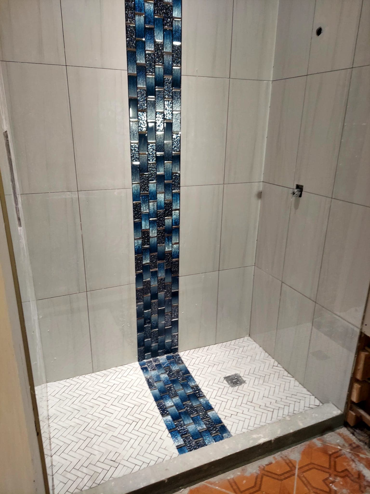 Residential shower with light tile and blue mosaic accents